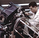 A researcher in a labcoat examining a complex engine